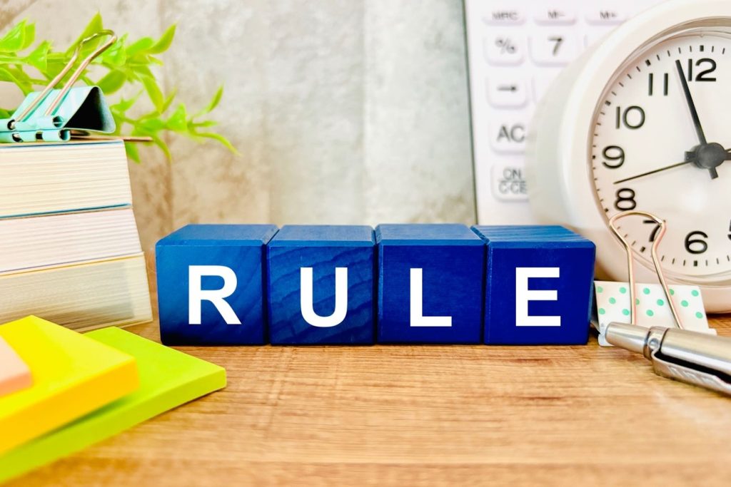 オフィスデスクにRULEと書かれた積み木が置かれている