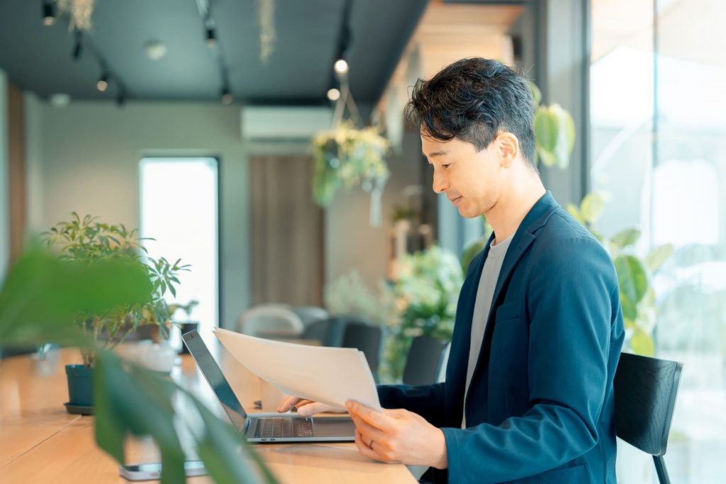 資料を見ながらサイト更新する男性