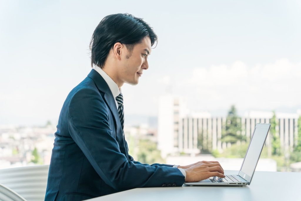 ノートパソコンで求人サイトのデータを入力している男性