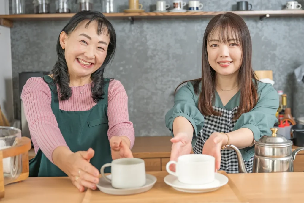 喫茶店でコーヒーを出す2人のカフェ店員