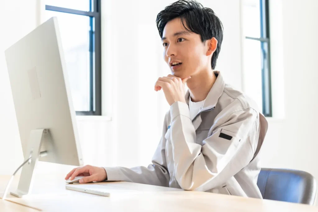 建設業求人サイトを見る作業服を着た男性